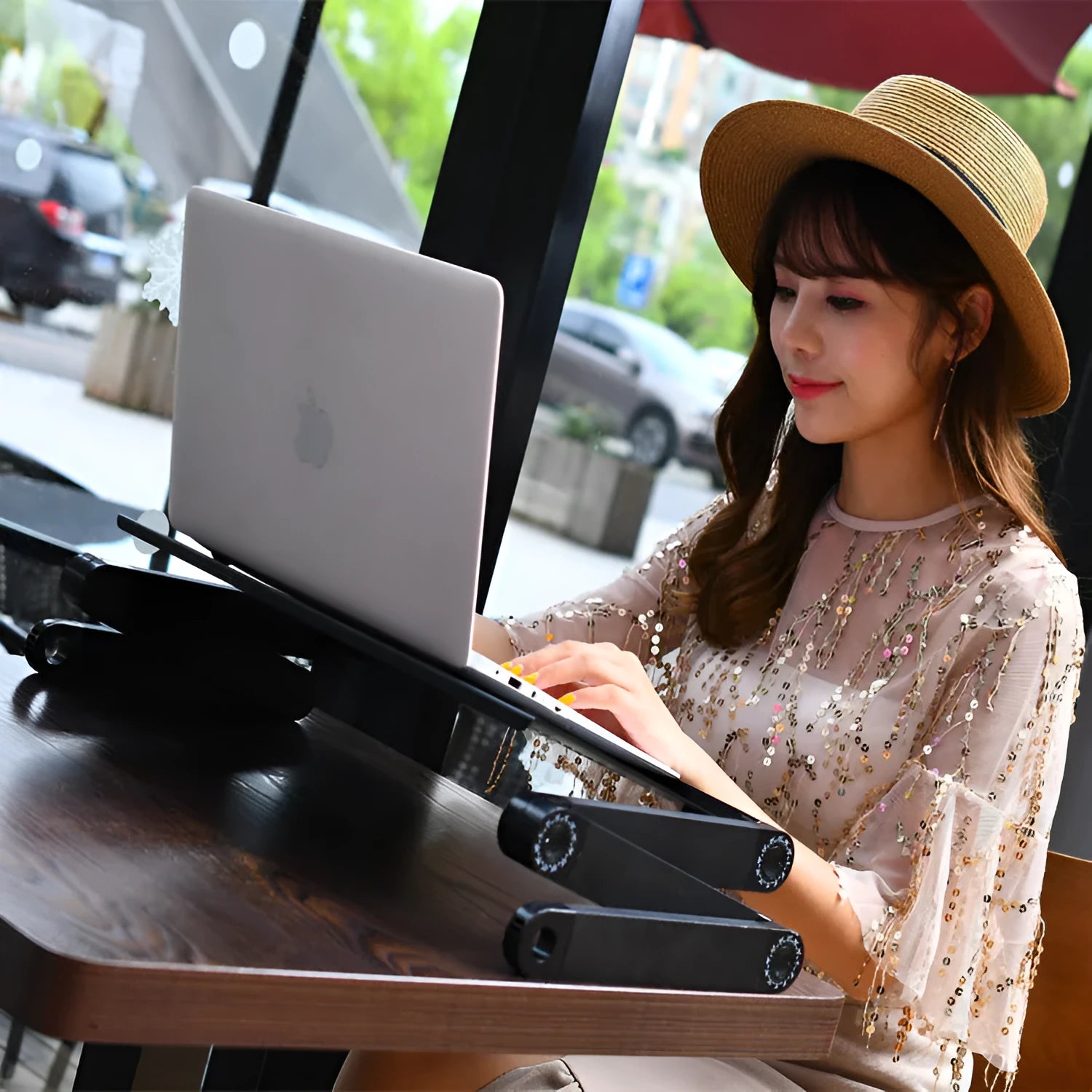 Black folding metal laptop desk with cooling holes extended over sofa