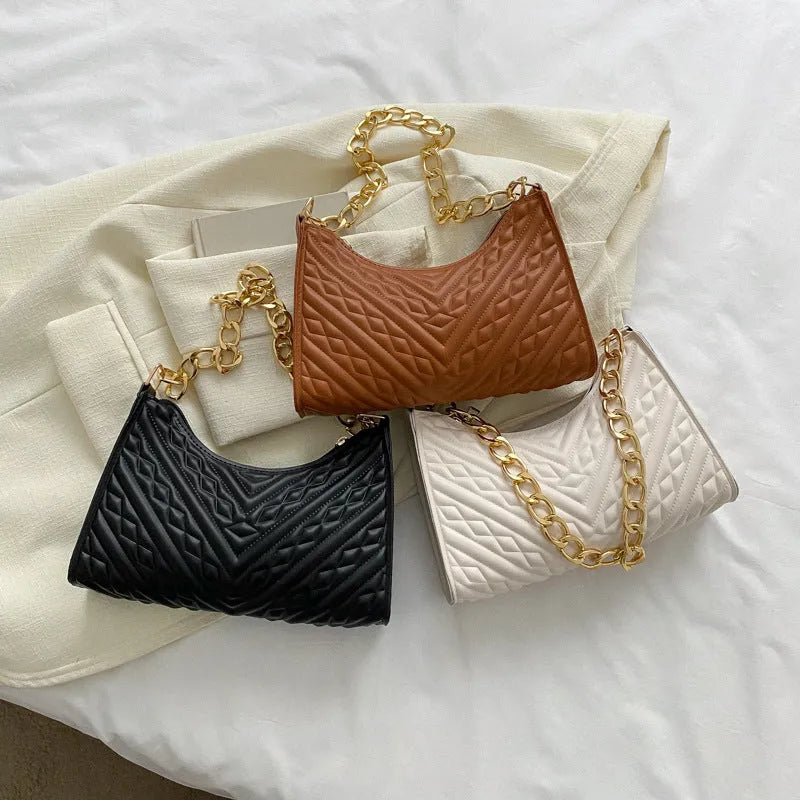 Brown pleated chain baguette women's shoulder bag with adjustable strap on a mannequin.