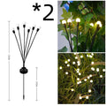 Solar-powered LED firefly garden spike light with stainless steel ground stake illuminated at dusk.