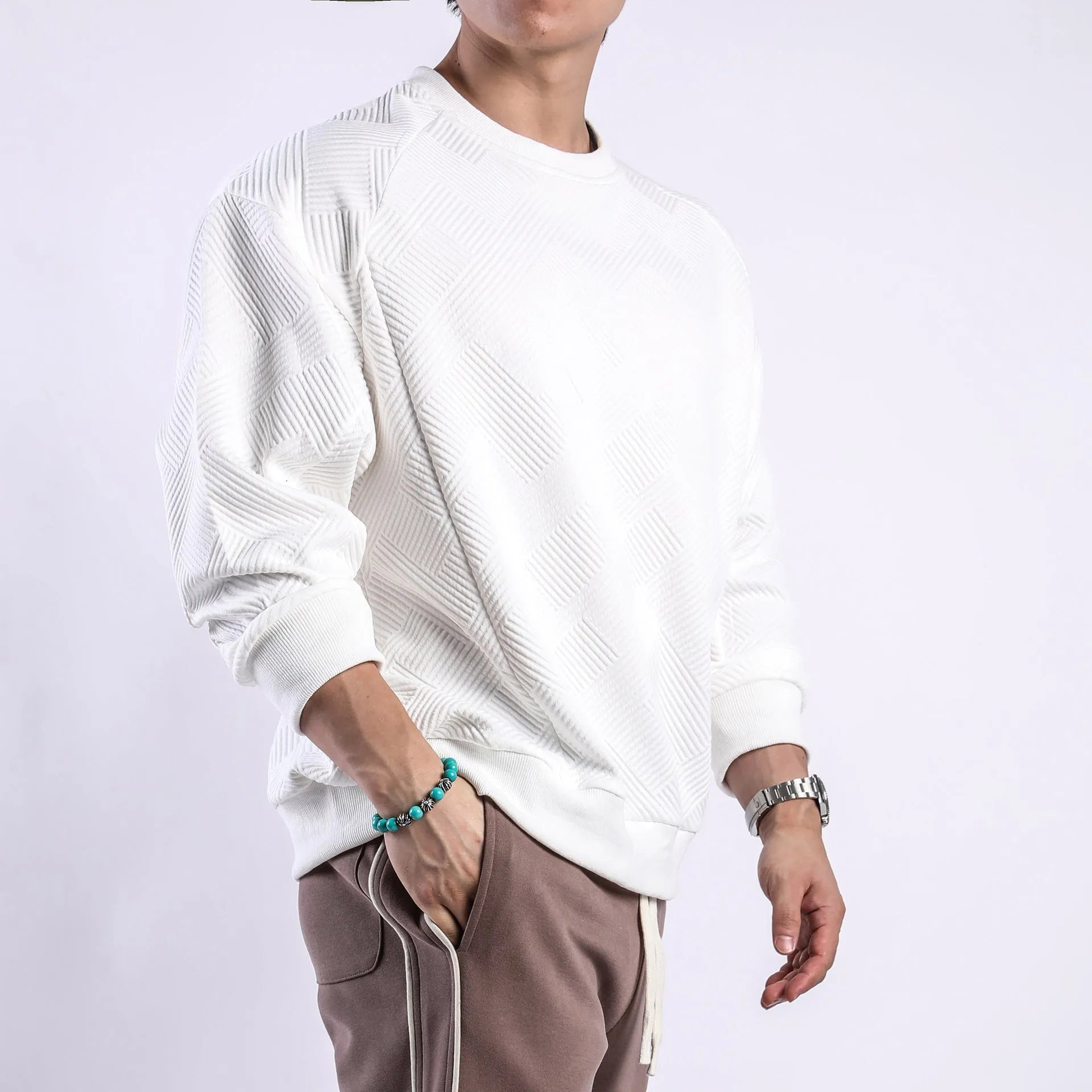 Man wearing a loose-fit, long-sleeved twill jacquard sweater in a solid colour with a round neck.