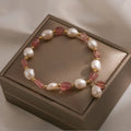 Handmade strawberry quartz crystal bracelet with Hetian jade peach blossom charm on a wrist.