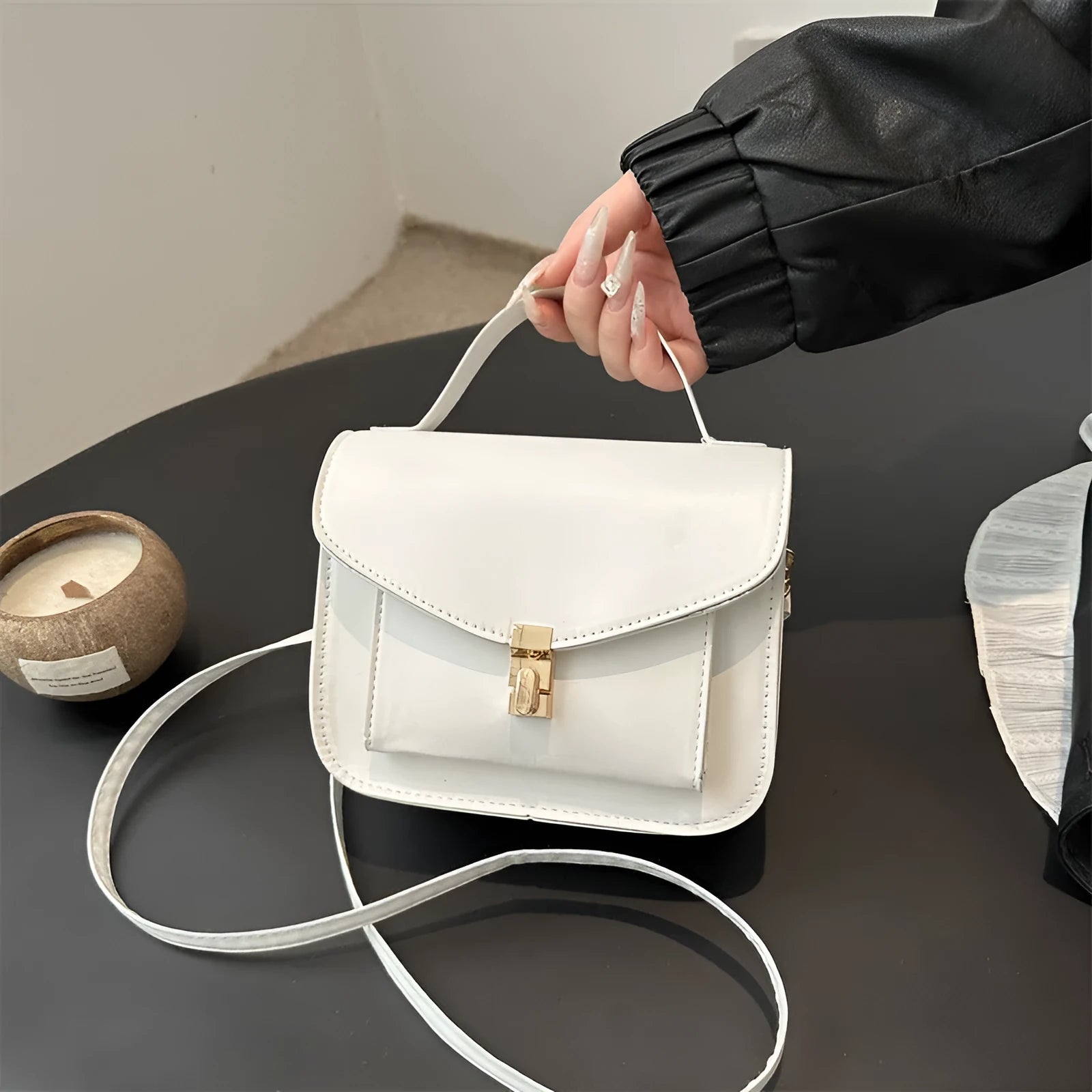 Horizontal square black PU messenger bag with a front sandwich pocket and visible sewing lines.