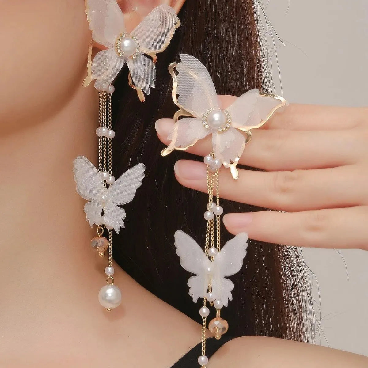 White butterfly-shaped earrings with lace detail, pearls, rhinestones, and a dangling tassel.