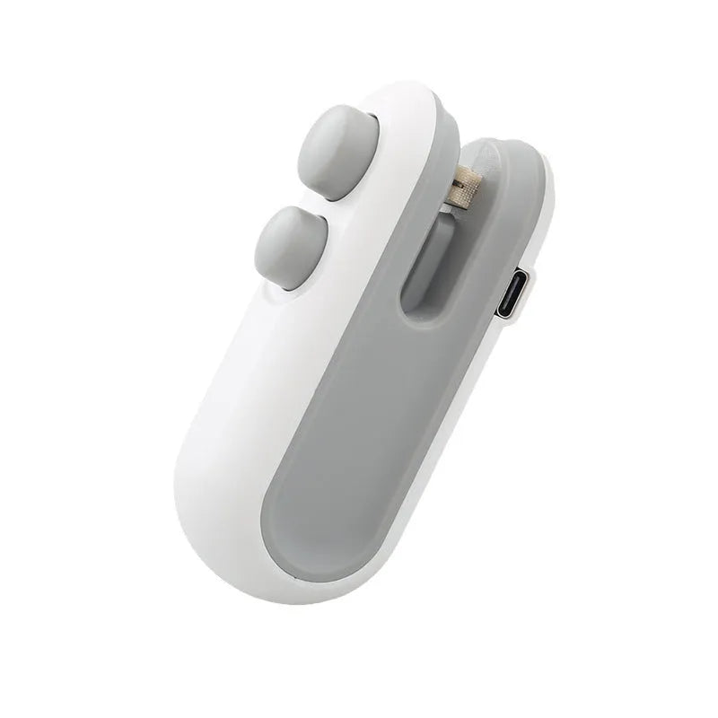 White and blue handheld USB heat sealer with cutter blade on a kitchen counter.