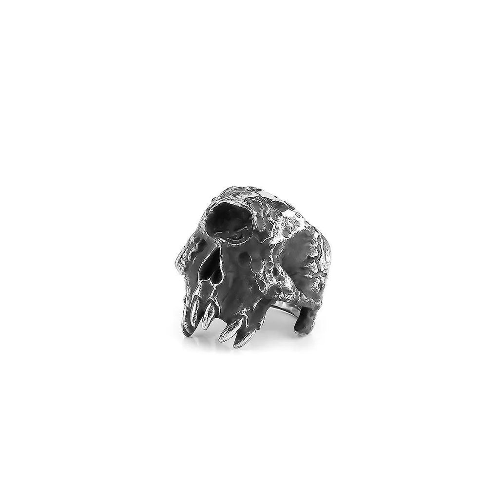 Close-up of a retro alloy ring with a detailed one-eyed skull design on a dark background.