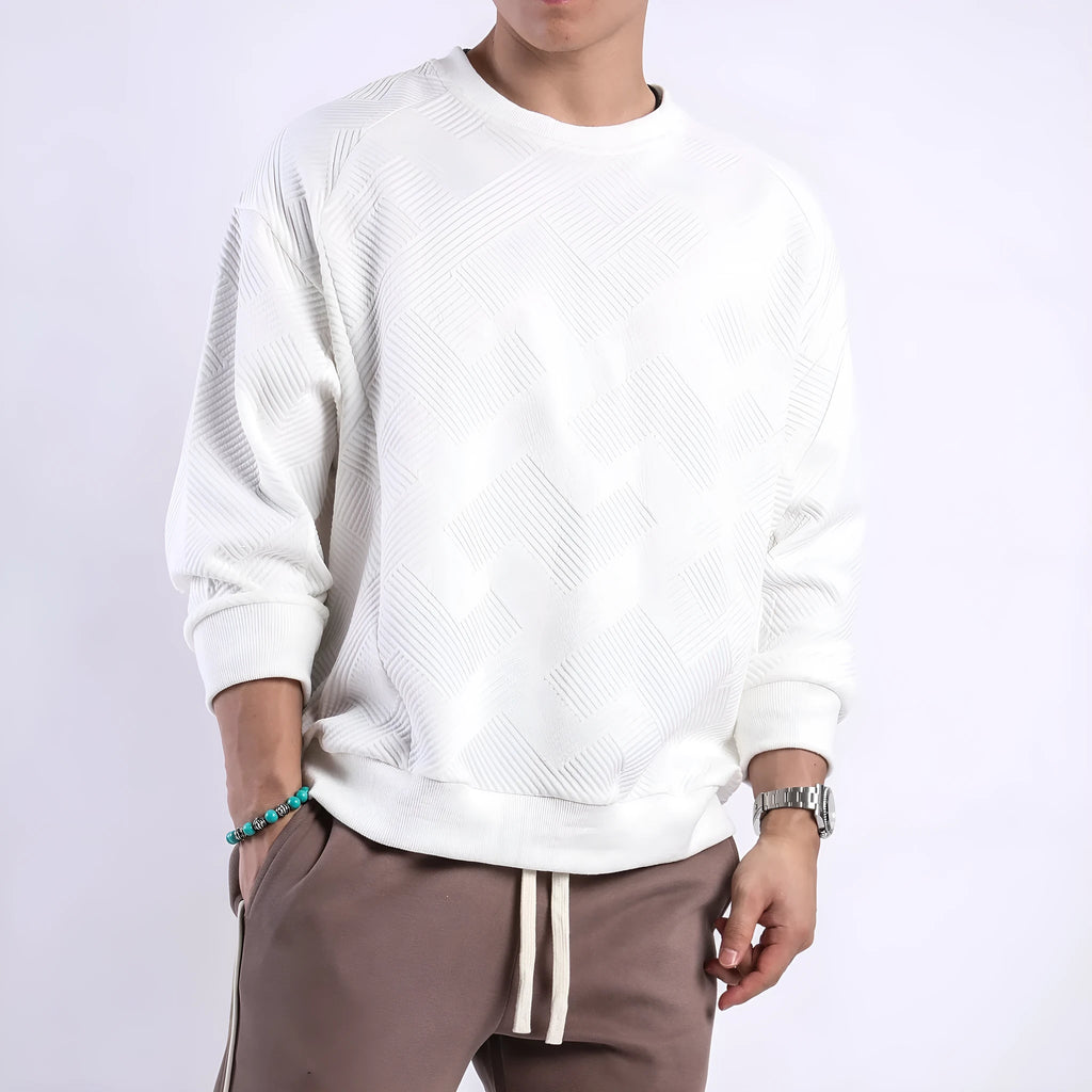Man wearing a loose-fit, long-sleeved twill jacquard sweater in a solid colour with a round neck.