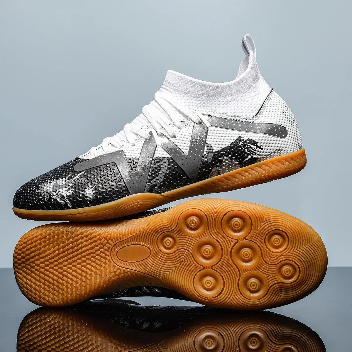 Low-top soccer boots in black and yellow colourway with spiked rubber sole, shown on a firm ground surface.