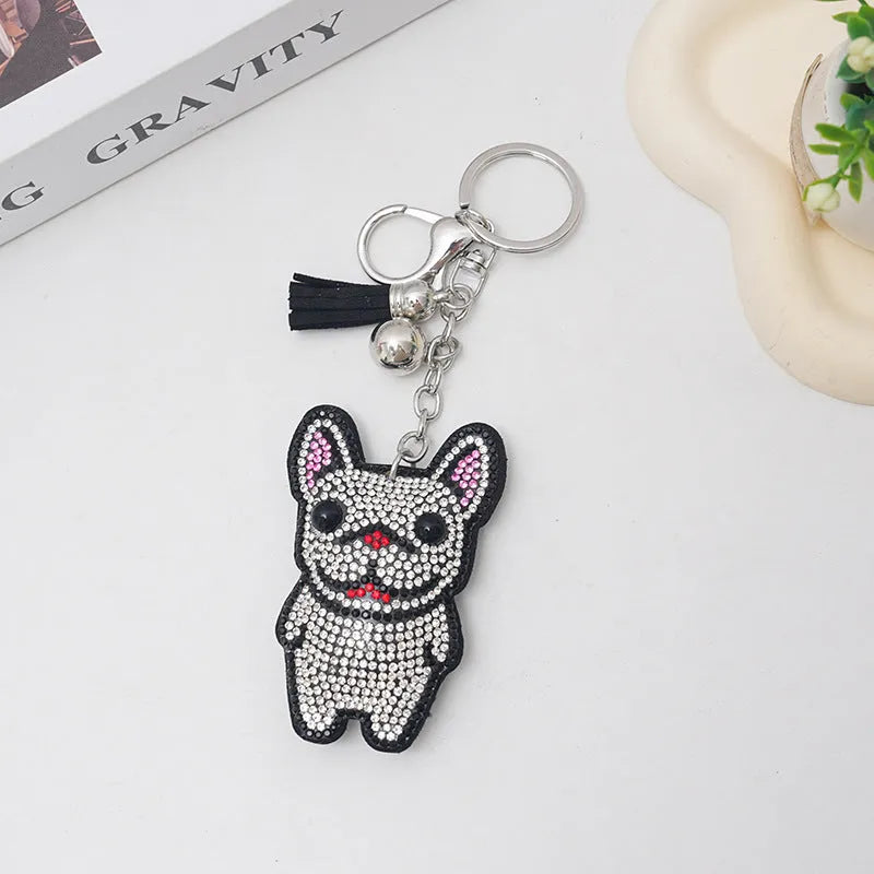 Close-up of a French dog style cartoon bear rhinestone keychain charm on a keyring.