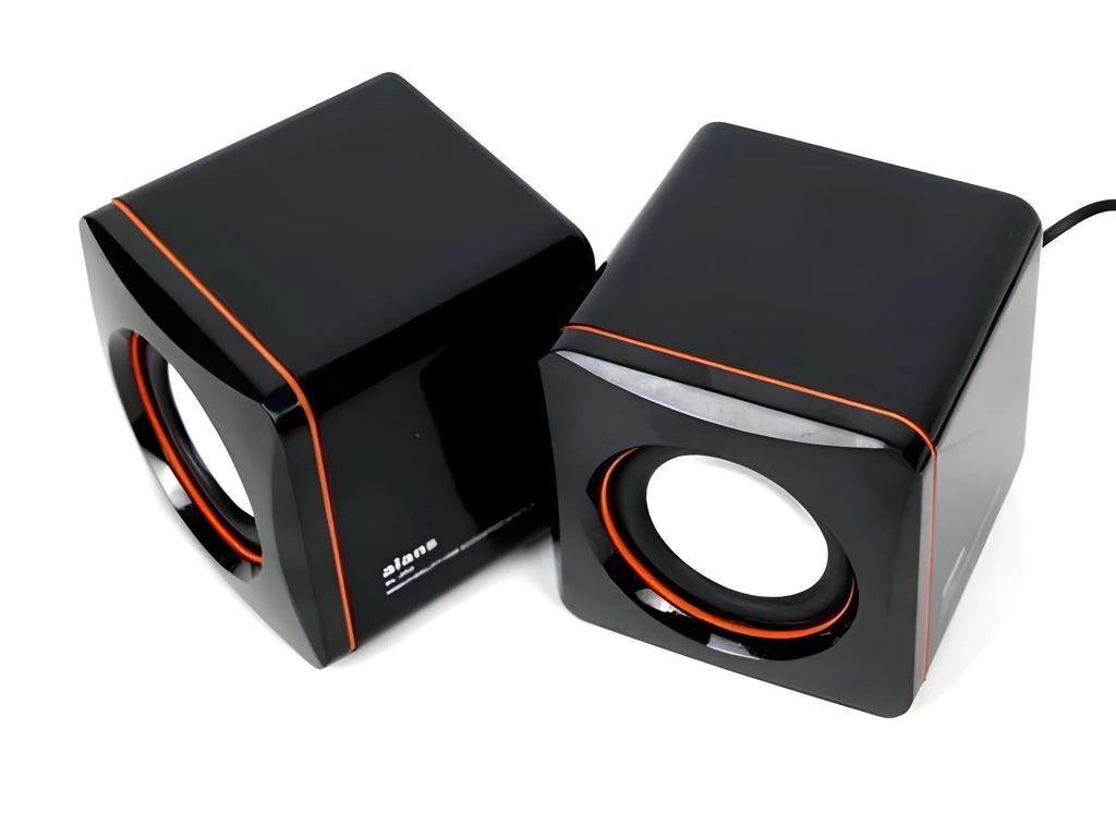 Small black square USB-powered 2.0 computer speaker on a desk next to a laptop
