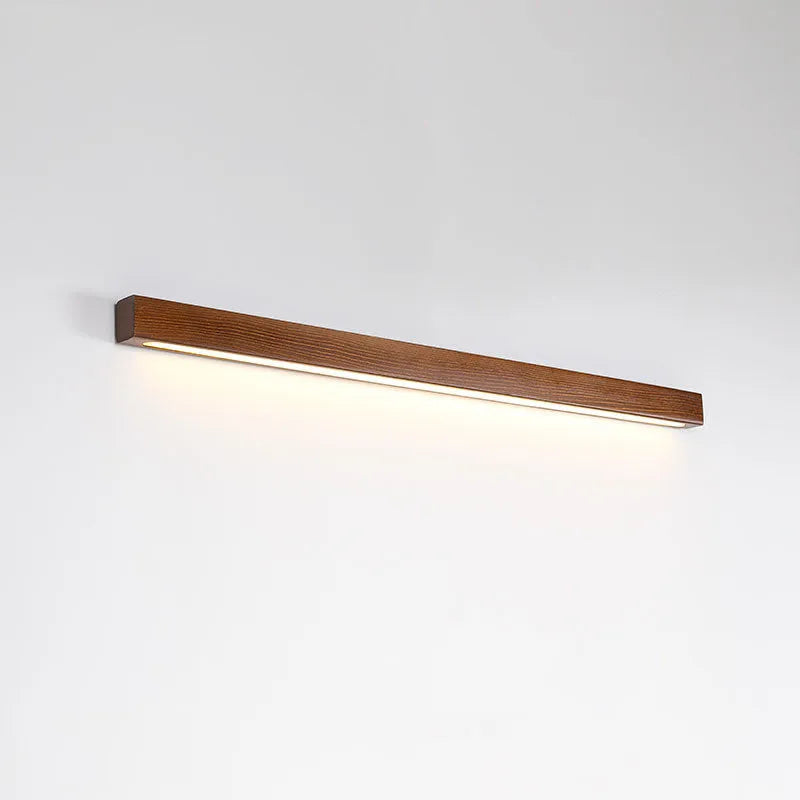 Walnut-coloured wood and acrylic minimalist LED strip wall lamp in three sizes on a white wall.