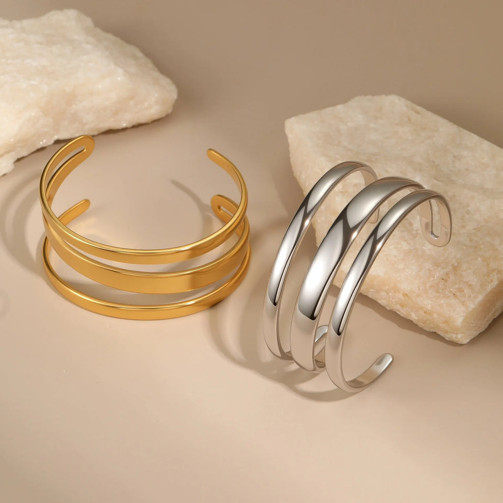 Women's stainless steel bracelet with geometric line design, shown in gold and steel finish options.