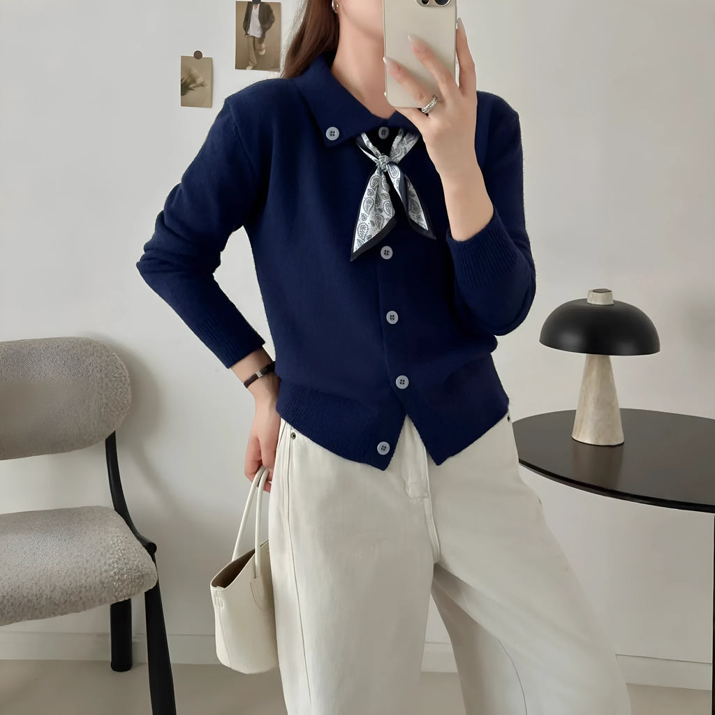 Beige acrylic cardigan with lapel scarf collar and splicing detail on a hanger.