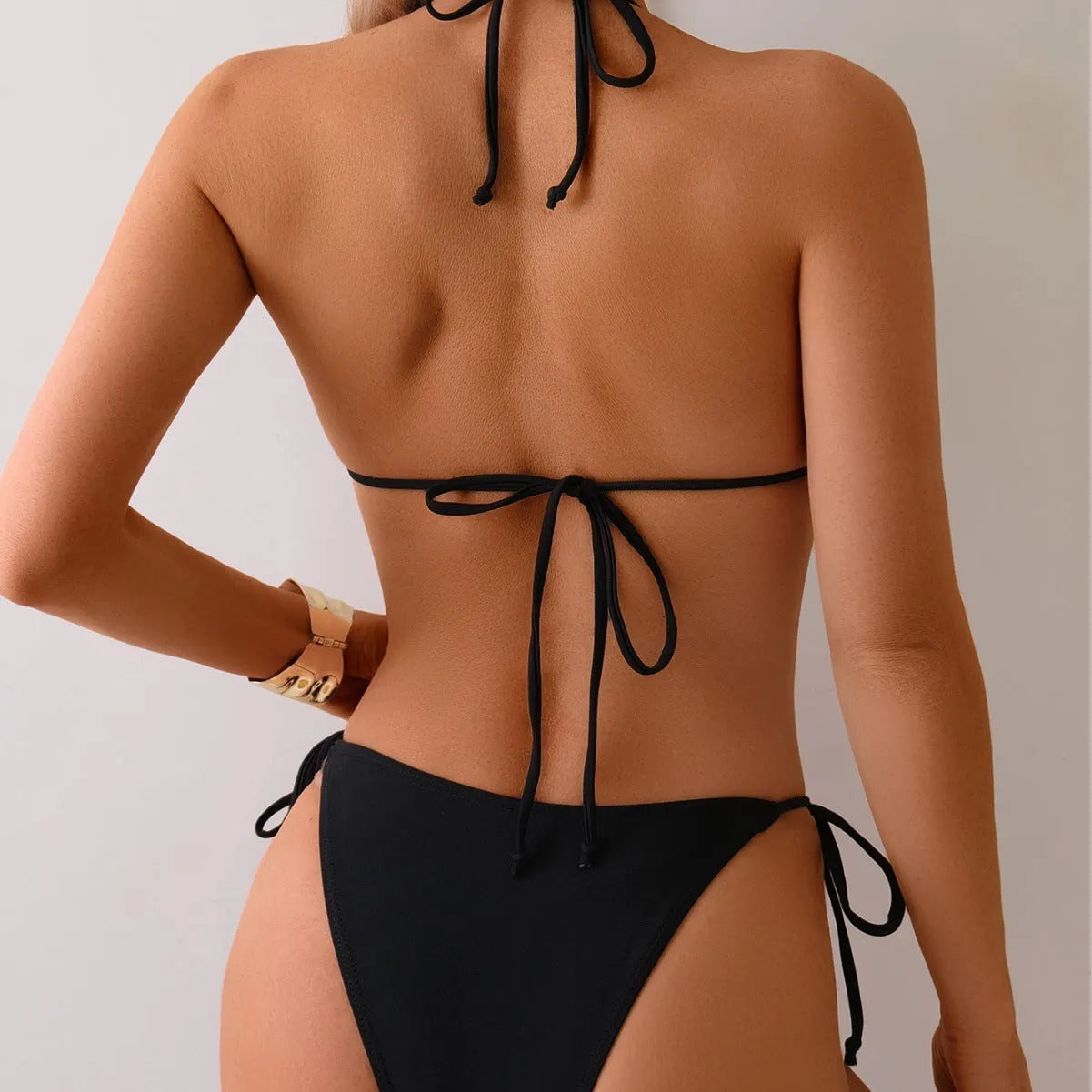 Black women's bikini swimsuit with metal bead decoration and split-side design.