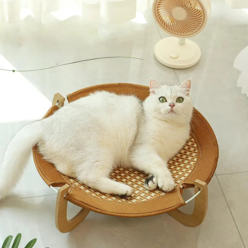 Natural brown woven rattan pet hammock with raised sides on a wooden floor.