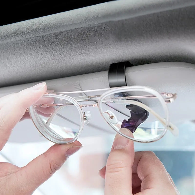 Black plastic car sun visor clip organiser for glasses and cards on a car interior.
