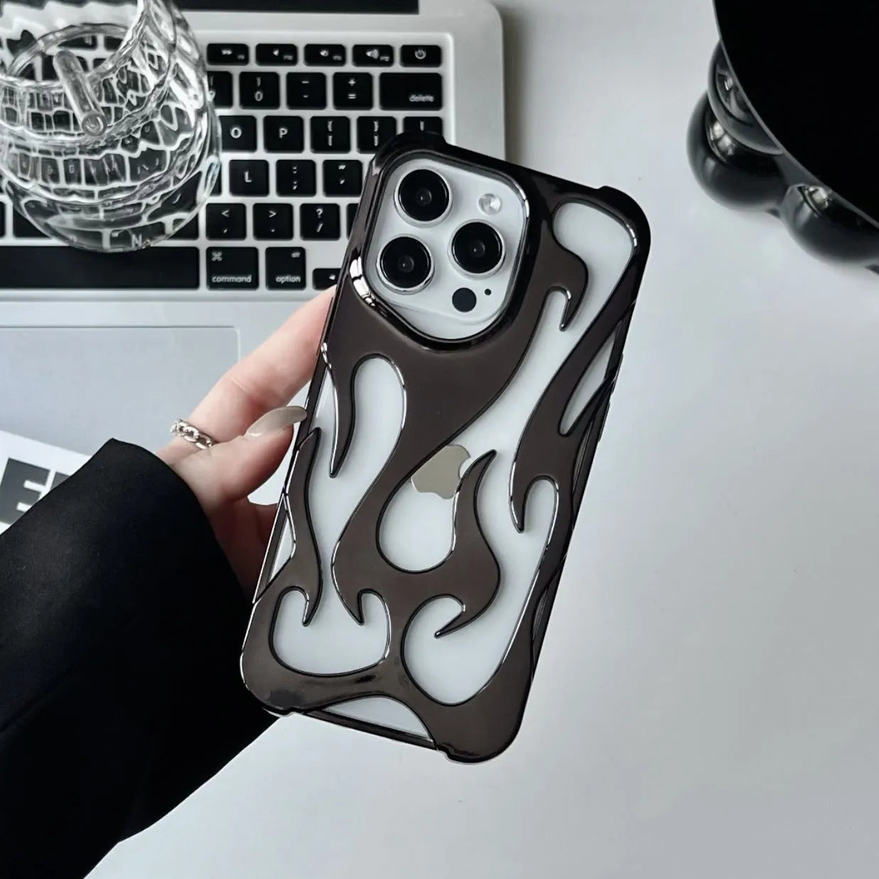 Apple iPhone case with hollow flame pattern and electroplated finish in silver, shown on a phone.