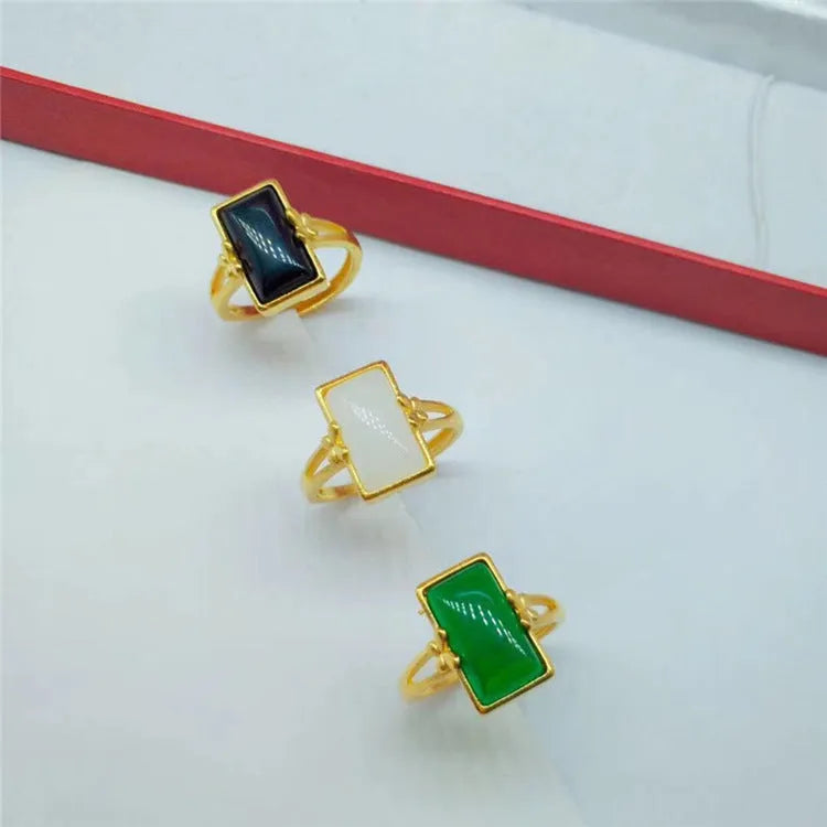 Adjustable brass gold-plated ring with a long black gemstone inlay on a finger.