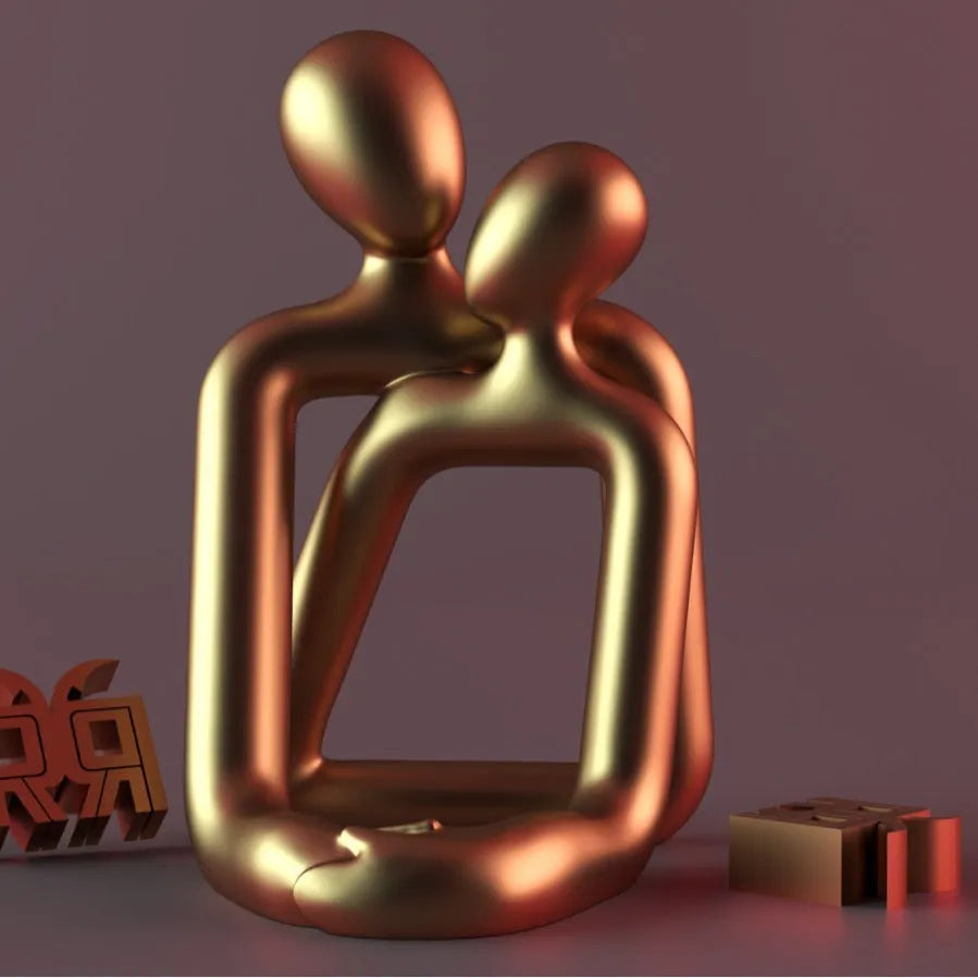 Modern couple resin statue in gold finish on a wooden desk.