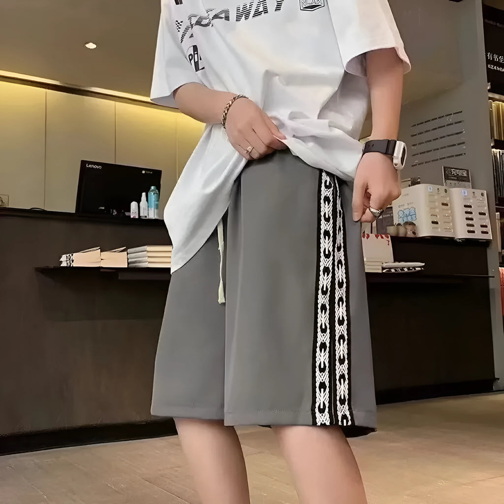 Man wearing loose-fit black track pants made from polyester with a micro-elastic fabric.