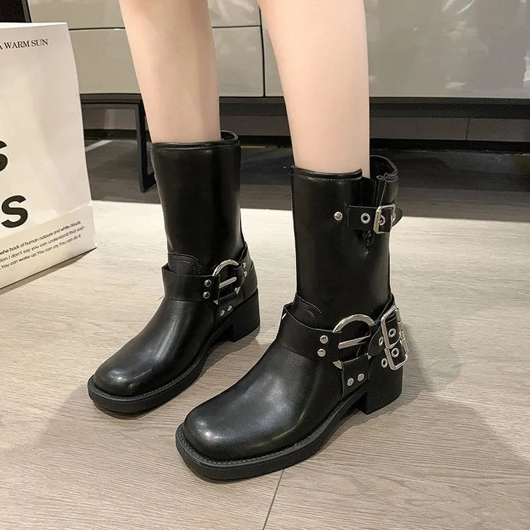 Women's black platform boots with a large silver belt buckle and mid-calf height.