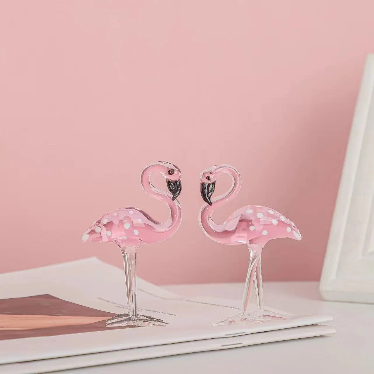 Clear crystal flamingo decorative sculpture with pink dots on a table.