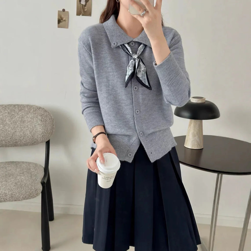 Beige acrylic cardigan with lapel scarf collar and splicing detail on a hanger.