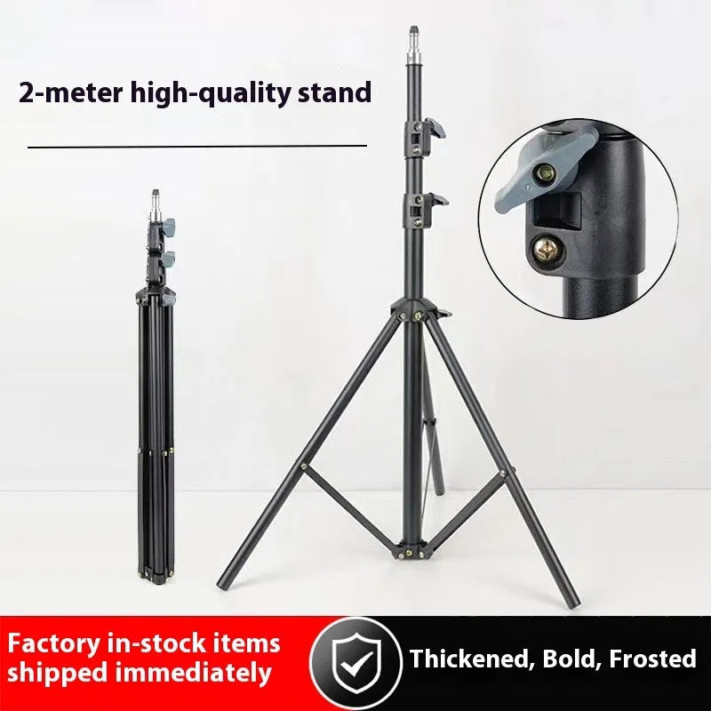 A frosted finish floor tripod light stand at full height with a mobile phone holder attached.