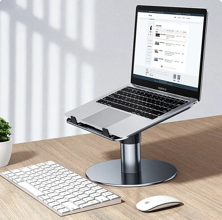 Silver adjustable aluminium laptop stand with rotating base on a desk.