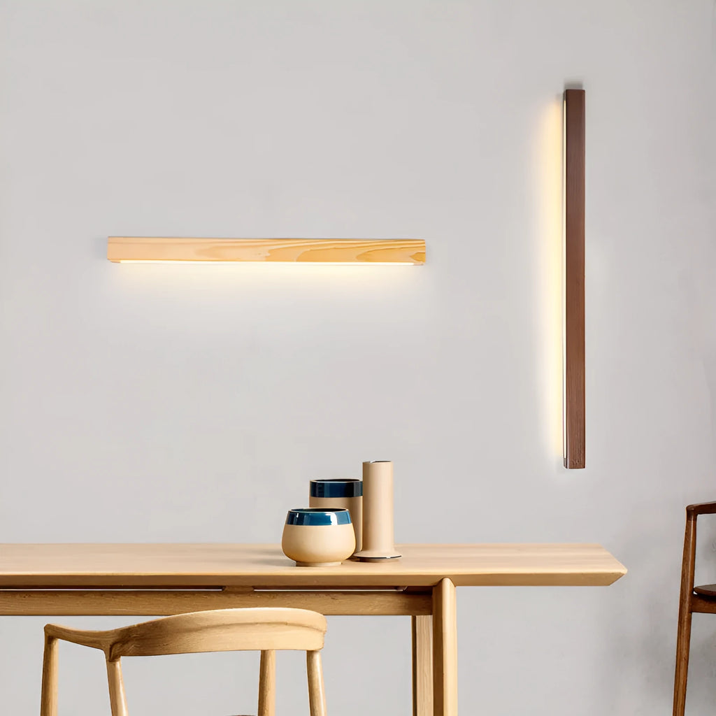 Walnut-coloured wood and acrylic minimalist LED strip wall lamp in three sizes on a white wall.