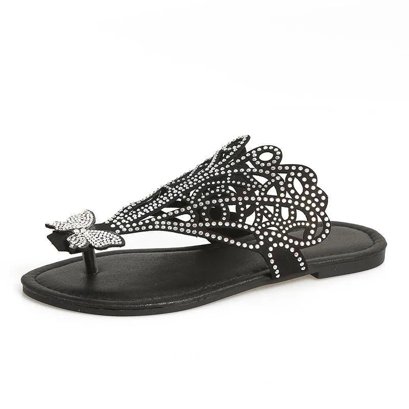 Women's black flip-toe sandals with rhinestone details on the hollow-out PU upper and a flat rubber sole.