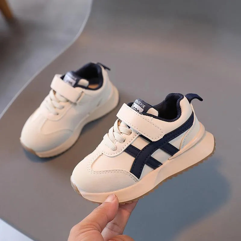 Children's white synthetic leather sneaker with Velcro strap and non-slip rubber sole.