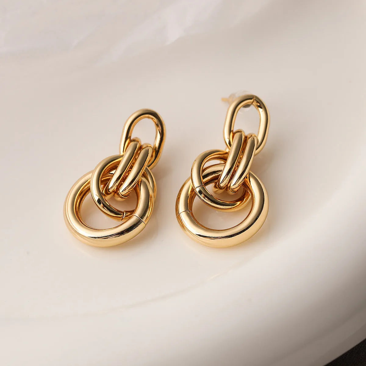 Geometric gold-coloured copper earrings with irregular design elements and high-profile construction