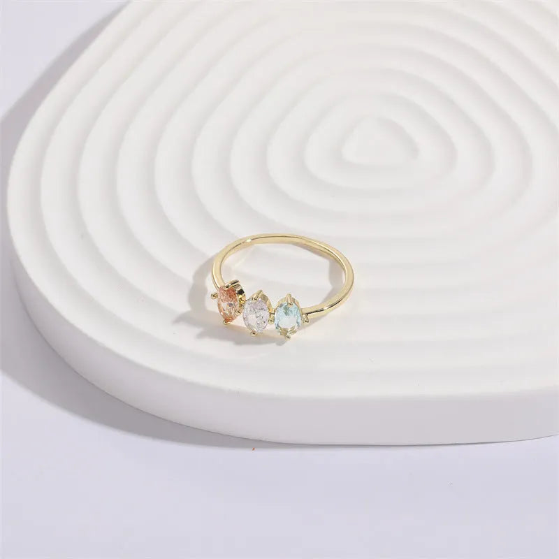 Geometric triangle ring with tricolour zircon birthstone in gold electroplated finish.