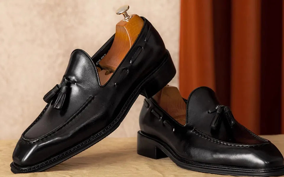 Men's black genuine leather slip-on loafers with fringed detailing on a white background
