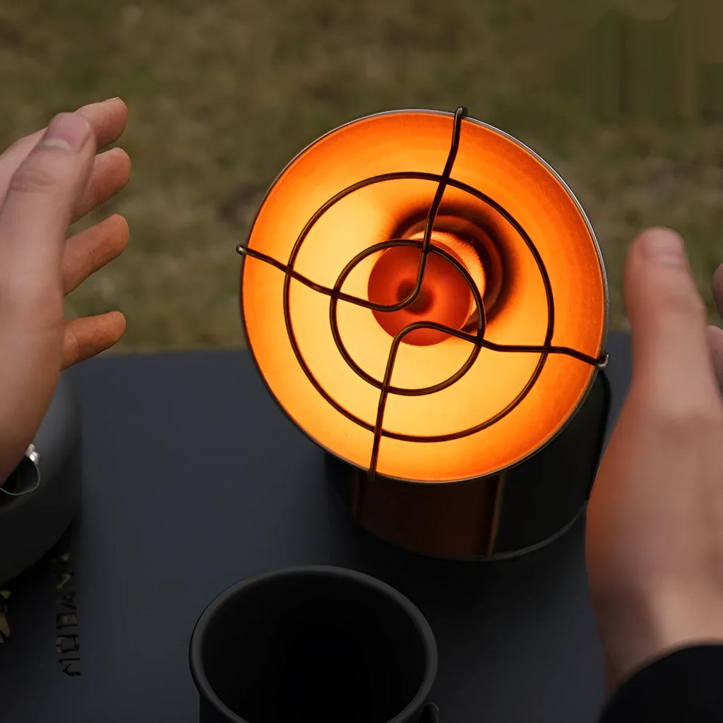 Black and orange mini portable outdoor heating stove with automatic ignition on a table.