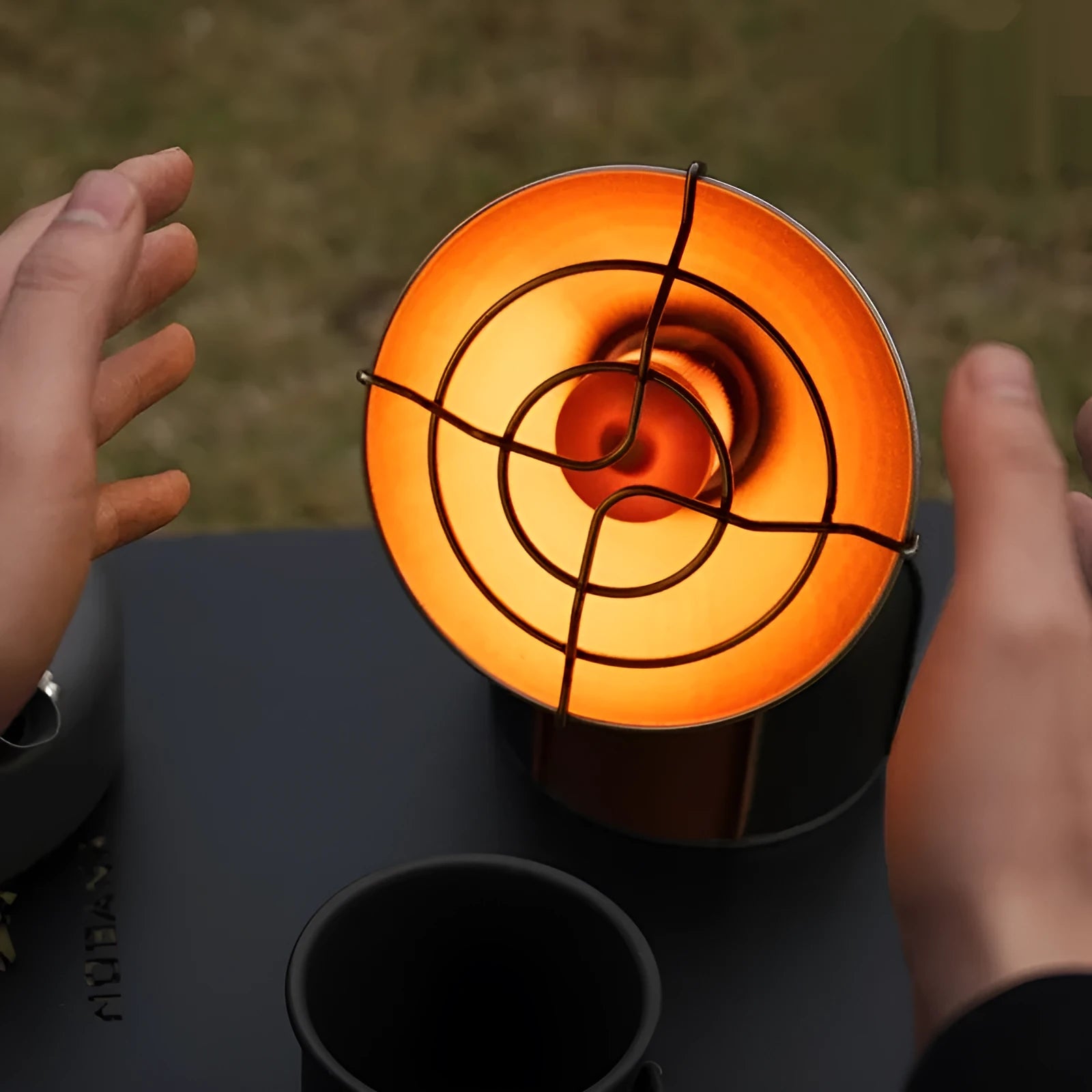 Black and orange mini portable outdoor heating stove with automatic ignition on a table.