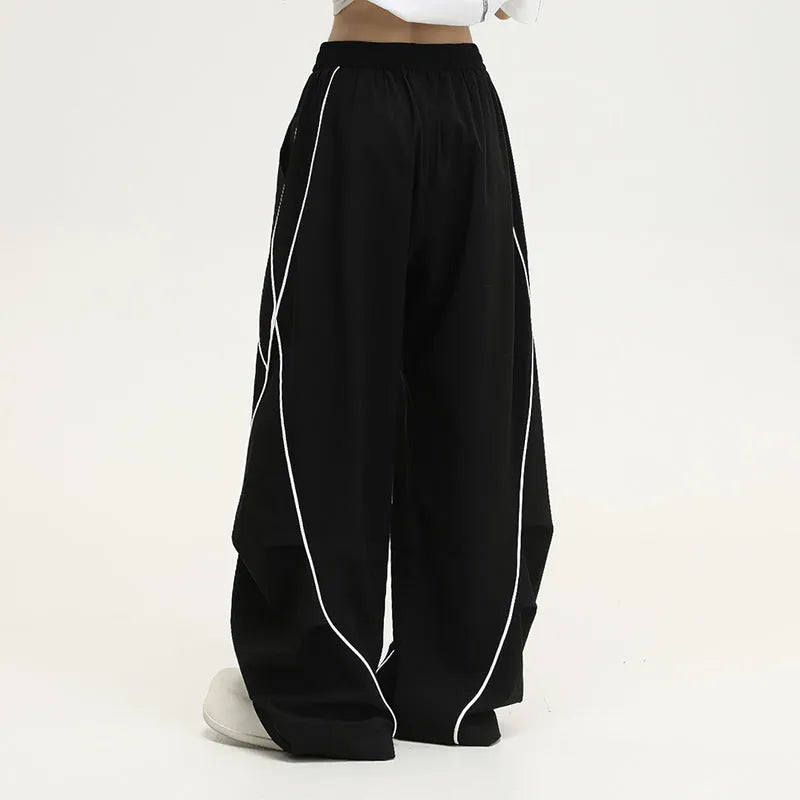 Black and white striped pleated wide-leg hip hop sports pants on a mannequin, showing loose fit and mid waist.