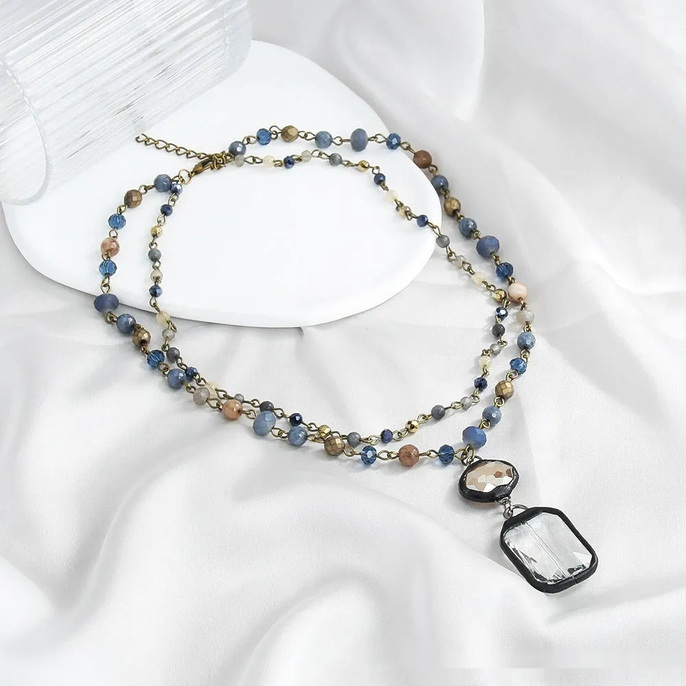 Tribal style two-layer chain necklace with glass and stone pendants in beige and blue colours