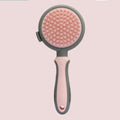 Pink and green double-sided cat grooming brush with a release button and a separate flea comb.