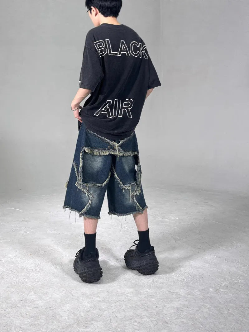 Blue denim shorts with frayed hem and star detail shown in loose fit style
