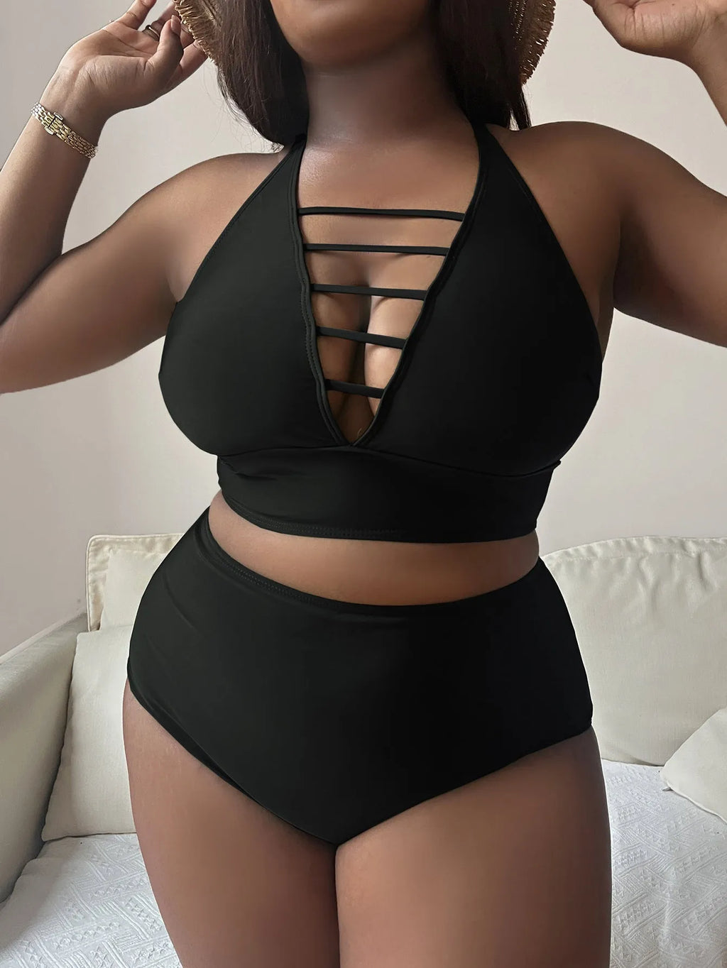Plus size woman in a black halter bikini with cross-back straps and high-waist briefs on the beach.