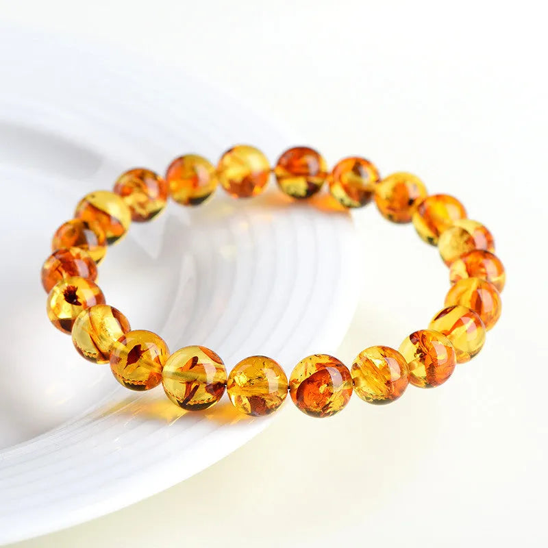 Natural yellow piebald amber bracelet with geometric beads on a white background.