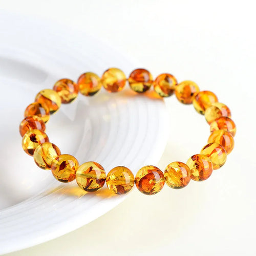 Natural yellow piebald amber bracelet with geometric beads on a white background.