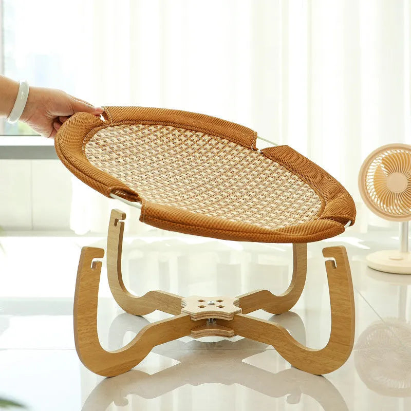 Natural brown woven rattan pet hammock with raised sides on a wooden floor.