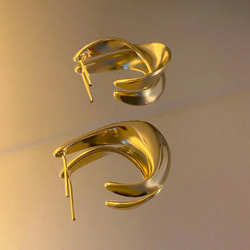 Metal twisted geometric earrings with electroplated gold or silver finish showing round design elements