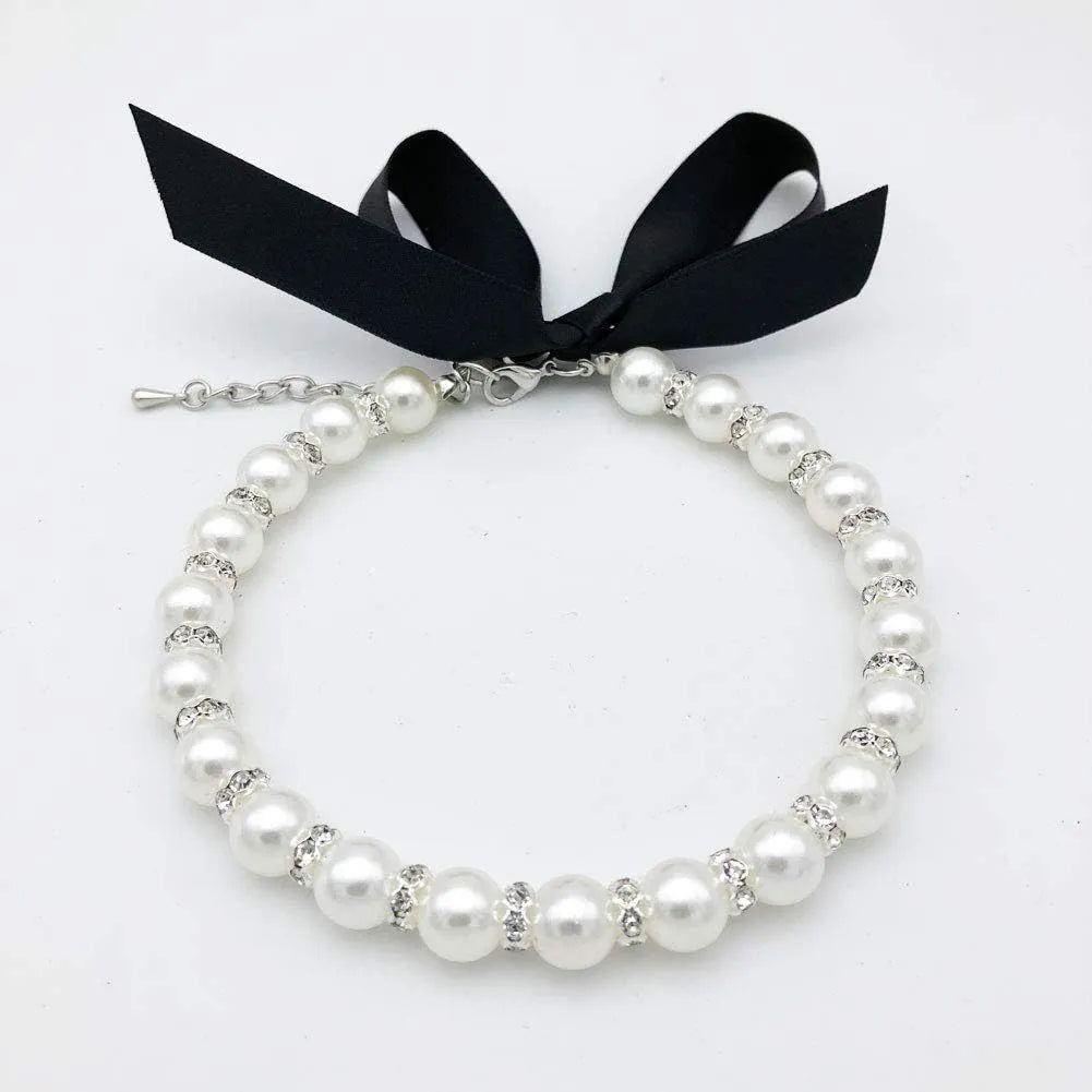 Small dog wearing adjustable pearl necklace with rhinestones and ribbon bow decorative collar