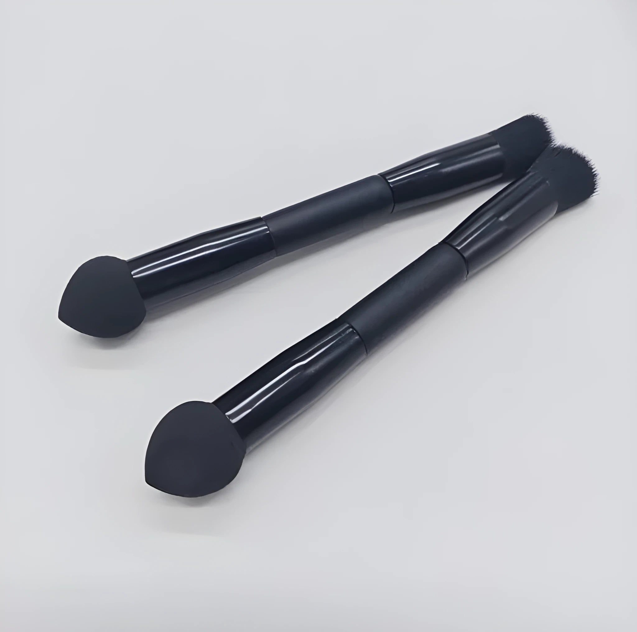 Elegant black double-headed makeup brush with a concealer brush and angled miter sponge on a wooden handle.