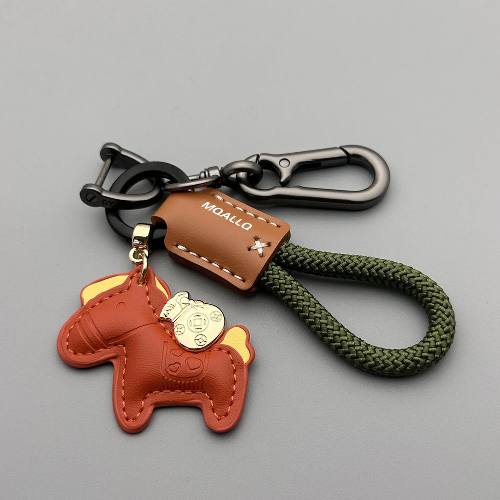 Handmade brown cowhide leather key ring with a gold pony belt buckle charm and a green flanelle rope loop.