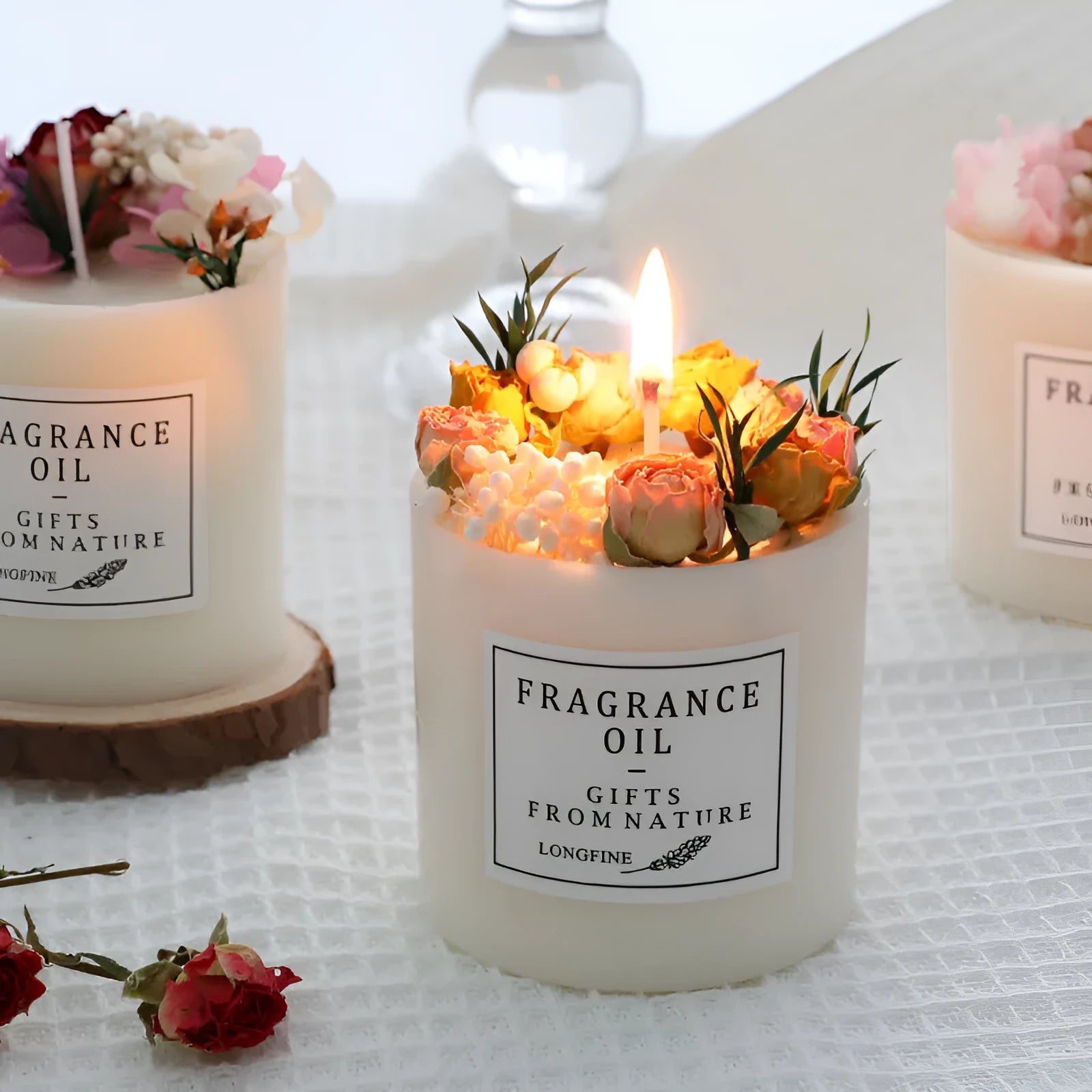 Aromatherapy candle with dried flowers embedded in wax, shown with optional wooden chip base and gift box.