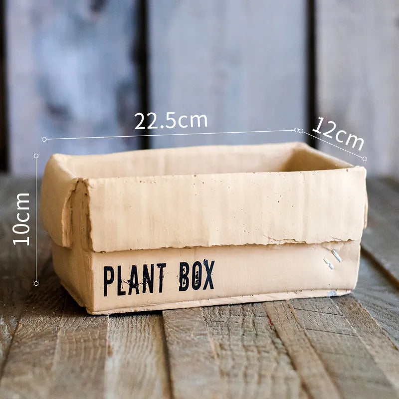 Cement flower pot with brown paper box texture and drainage holes, shown in a neutral home setting.